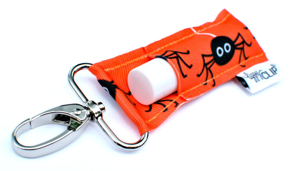 Orange lip balm holder with halloween spider design and silver clip.